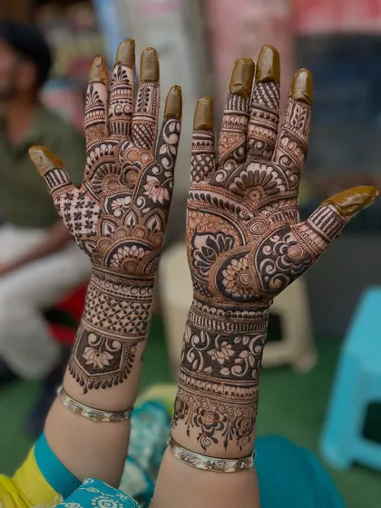 Another angle of the classic bridal design, highlighting the intricate work on the fingers and the detailed bands on the wrists.