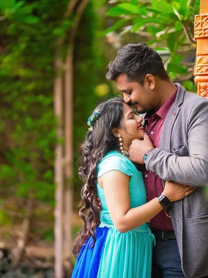 An intimate forehead kiss between a couple, framed by vibrant red pillars.
