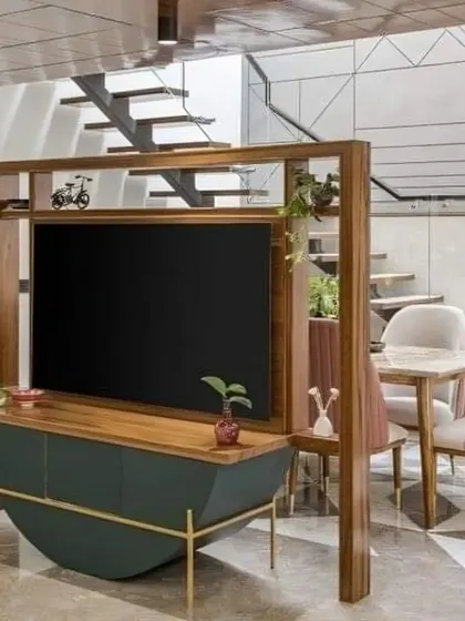 This innovative TV unit doubles as a room partition, cleverly separating the living and dining areas without closing off the space. The curved base and wooden frame add a unique, contemporary touch to this open-plan layout.