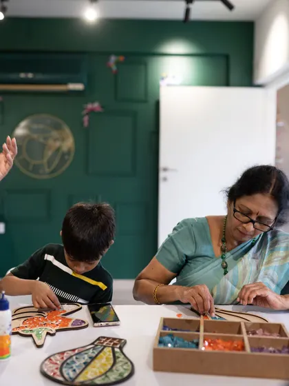 Art beautifully bridges generations. Here, a grandmother and her grandson are completely absorbed in their mosaic project, sharing a quiet moment of creativity.