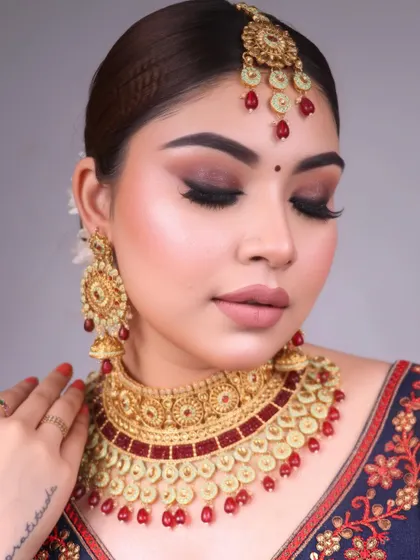 A beautiful traditional bridal look with a red and gold color palette, featuring a soft brown smokey eye and a classic red bindi.
