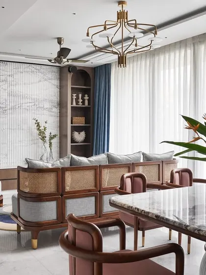 A view of the living room highlighting the custom-designed sofa and lounge chairs, which blend wood and cane for a rustic, Zen-like feel. The fluted Satvario marble TV unit wall adds a touch of opulence and visual height.