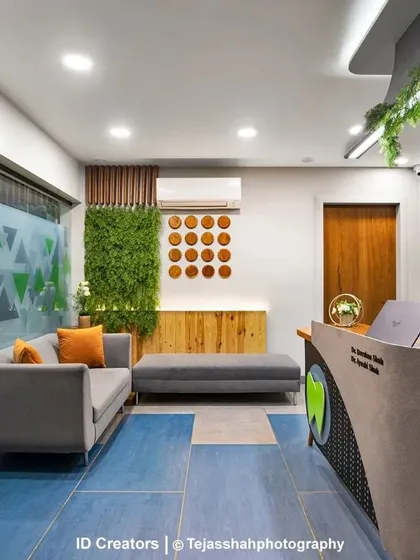 The 'Smile Dente' dental clinic in Vadodara features a welcoming reception and waiting area with a playful blue floor, comfortable seating, and biophilic elements.