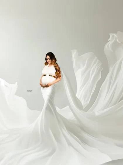 A breathtaking shot featuring a white gown with fabric tossed to look like angel wings. The clean, high-key background gives this portrait an ethereal and heavenly quality.