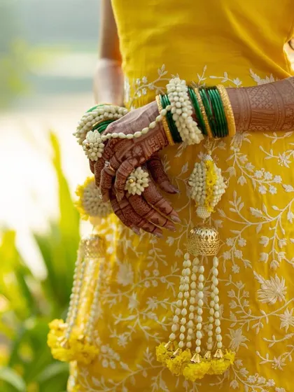 A detailed shot of the bride's hands, adorned with mehendi and our fresh floral haath phool and kalire. The combination of white mogra and yellow flowers is perfect for Haldi.