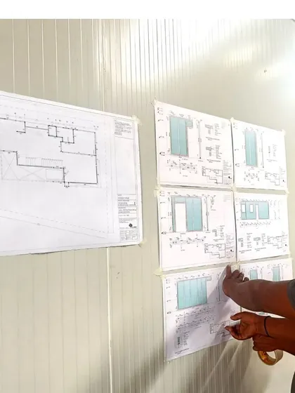 An architect reviewing the detailed drawings on-site against the installed panels. Precision is key when working with prefabricated systems, and we ensure every component fits perfectly as planned.