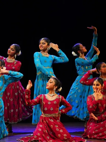 My talented students from the Sāttvatī School of Dance in a dynamic pose during our "ARAMBH" performance, dressed in vibrant red and blue costumes.