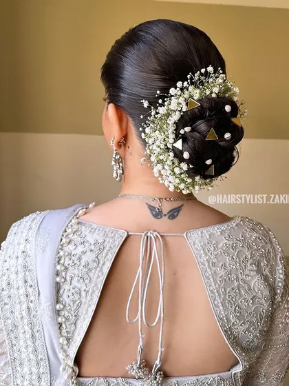 For this morning wedding, I created a neat bridal bun decorated with baby's breath, pearls, and unique triangular gold clips. This style is both traditional and modern, perfect for a bride with a distinct sense of style.
