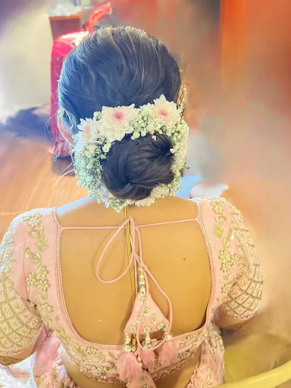 A beautiful bridal bun with a halo of fresh pink and white flowers. This is a classic and romantic look for any bride.