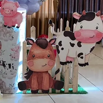 Adorable horse and cow cutouts with a small wooden fence prop. These details are perfect for creating a charming barnyard scene at a farm-themed party.
