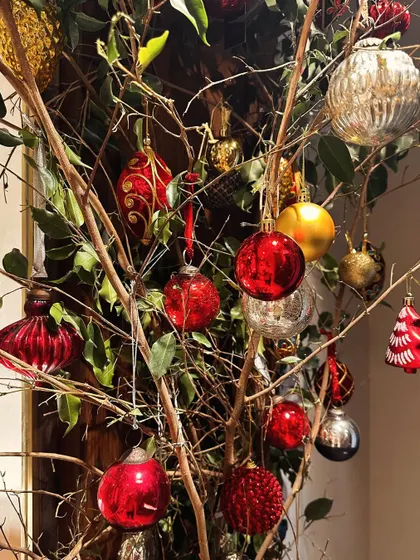 A creative way to display Christmas ornaments by hanging them on bare branches. This adds a rustic and artistic touch to your holiday decor.