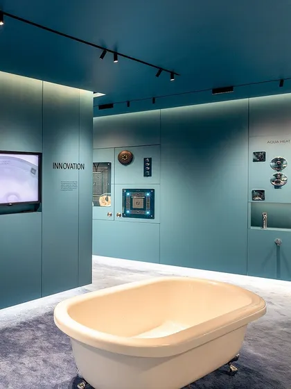 Another angle of the showroom, highlighting the contrast between the classic form of the bathtub and the modern, technical display of shower components on the wall.