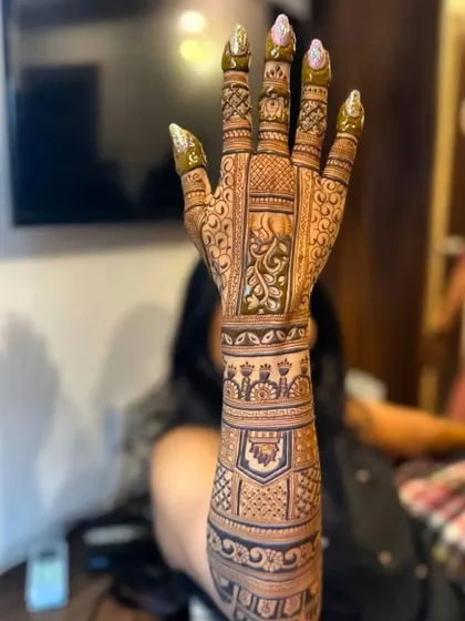 A client holding up her freshly finished mehndi. The dark paste will soon be ready to reveal a beautiful, rich stain.