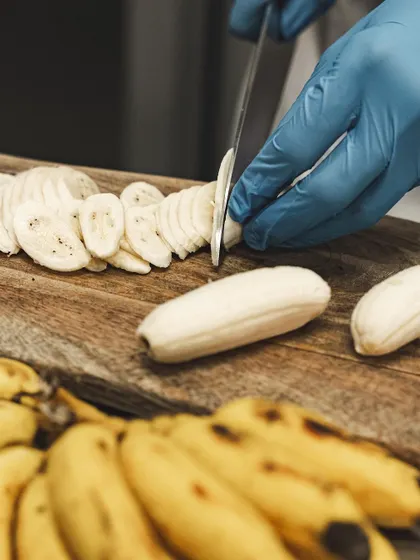 We use fresh, ripe bananas in our Banoffee Pie. Here, a chef is slicing them by hand before they are layered into the dessert.