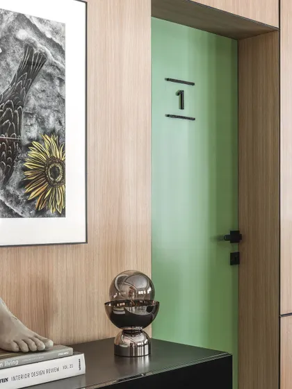 A close-up near the entrance to a consultation room. The combination of the green door, framed art, and decorative objects creates a welcoming and thoughtfully composed vignette.