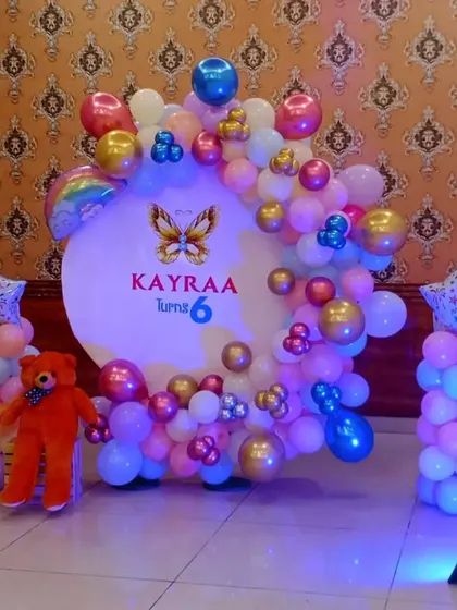 Another view of the butterfly-themed 6th birthday, showing the full setup with balloon columns and a teddy bear.