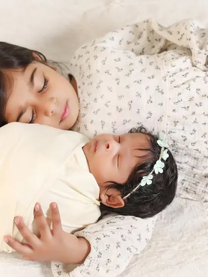 The quiet moments are often the most powerful. Here, an older sister peacefully rests beside her new sibling, a simple and beautiful portrait of their developing bond.