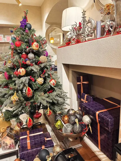 A cozy fireplace scene in our store, with a beautifully decorated Christmas tree and elegantly wrapped gifts, showcasing the complete holiday look.