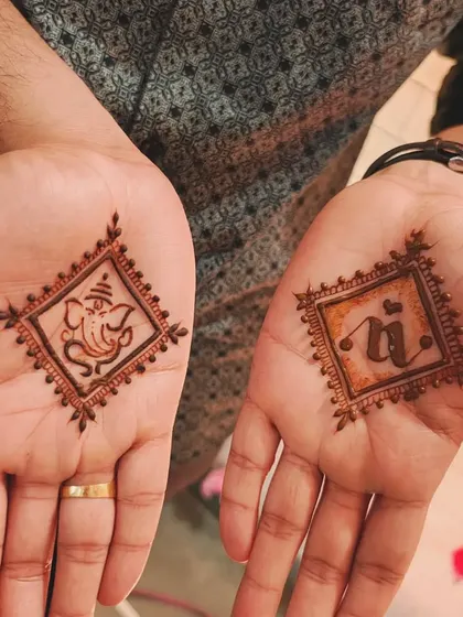 A minimalist groom mehendi with a purpose. One hand features Lord Ganesha, and the other has the bride's initial 'N', beautifully framed in a diamond shape.