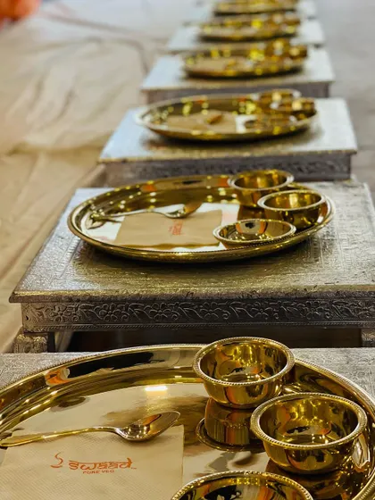 A line of perfectly arranged chowkis and golden thalis, ready for guests to be seated. I ensure every detail is in place to create a seamless and royal experience.