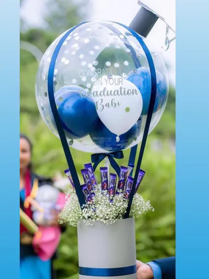 Celebrate their big achievement with a graduation themed hot air balloon hamper. This one includes a graduation cap detail on the balloon and a base filled with chocolates and flowers.