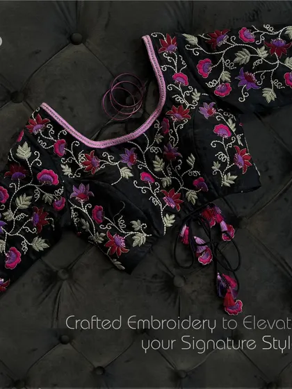 Intricate details, timeless appeal. This black designer blouse with vibrant floral embroidery defines luxury. The unique neckline and tassel ties are crafted to elevate your signature style.