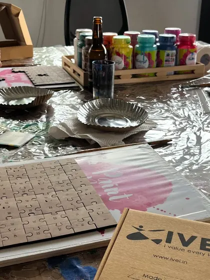 The setup for our puzzle painting workshop, with blank puzzles, paints, and a beer to help get the creative juices flowing.
