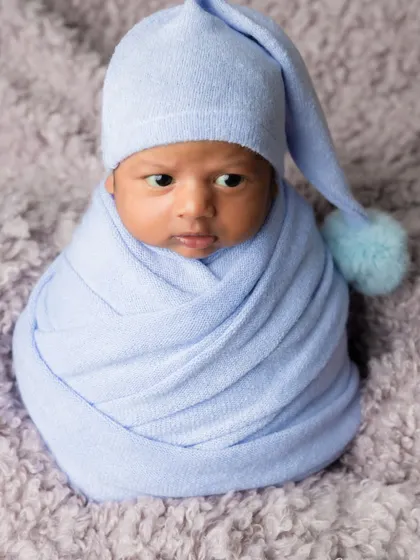 A precious awake moment from the same session, this little one looks around with curiosity from his cozy blue wrap.
