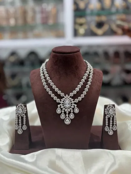 A double-layered AD necklace set with a central pendant. This versatile design comes in multiple colors including pink, white, emerald, and sapphire blue, making it a great addition to your inventory.