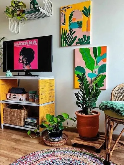 A design inspiration showcasing a bohemian and eclectic interior. The mix of colorful art, natural textures like rattan, and a variety of indoor plants creates a vibrant and personalized living space.