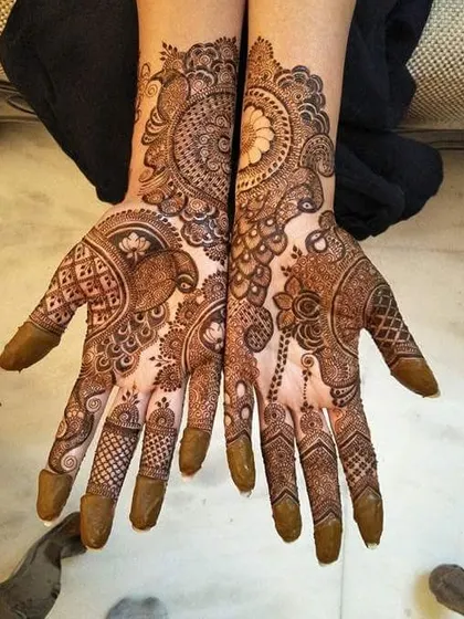 A full and intricate design for the palms, featuring a mix of peacock and floral motifs with a beautiful dark stain.