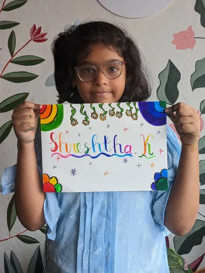 A young artist proudly holding up her colorful calligraphy nameplate, a beautiful piece of personalized art.
