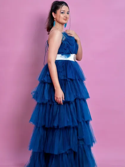 A full side view of the peacock blue ruffle gown.