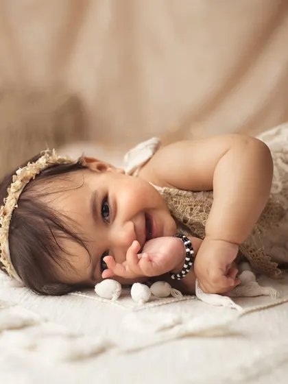 I just can't handle this level of cuteness. Her shy smile and playful pose on the soft blanket melt my heart every time.