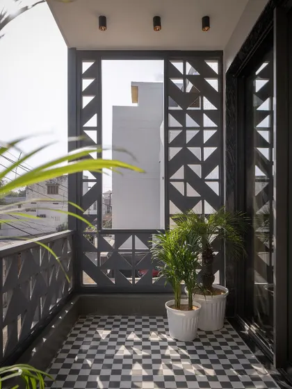 The balcony space, with its checkered floor and potted plants, shows how even small outdoor areas can become personal retreats. The screen provides privacy without sacrificing light or air.