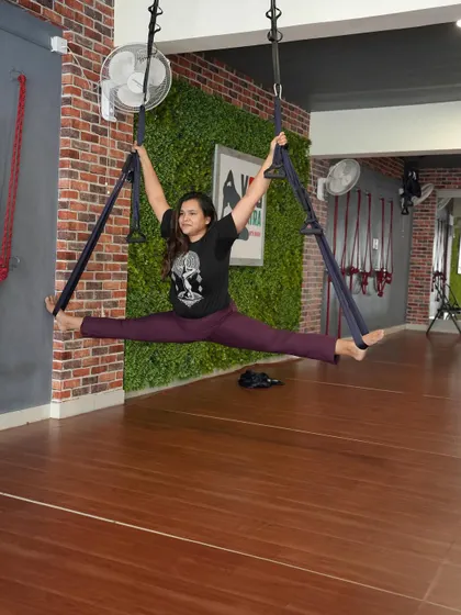 A wide-legged split in an aerial yoga hammock, a fun way to work on flexibility.