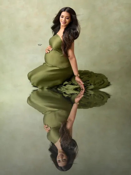 Let's get creative with some artistic shots. This stunning reflection portrait in an olive green gown adds a unique, high-fashion touch to your maternity gallery, creating a truly memorable image.