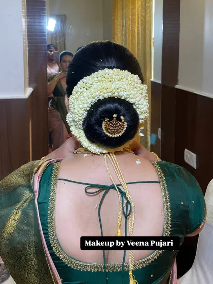 A classic South Indian bridal bun, completely covered in fresh jasmine flowers and finished with a traditional piece of hair jewelry. This style is timeless and fragrant.