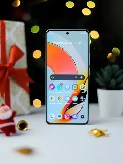 The front of the realme 10 Pro+ 5G, with its screen lit up, surrounded by Christmas gifts and ornaments.
