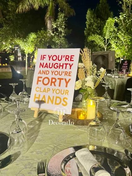 A playful sign for a 40th birthday that reads, "If you're naughty and you're forty clap your hands," adding a fun, interactive feel to the decor.