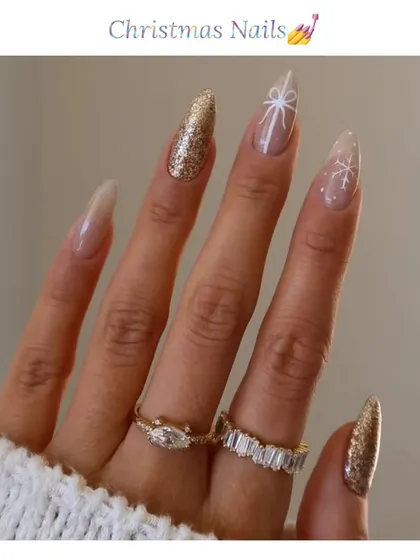 Get into the holiday spirit with these elegant Christmas nails. This almond-shaped set features gold glitter accent nails and delicate, hand-painted white snowflakes on a sheer base.