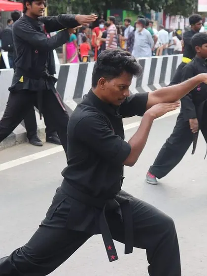 A student demonstrates a strong, low stance during a public demonstration at the Happy Streets event. This foundational posture is key to generating power and maintaining balance in Kung Fu.
