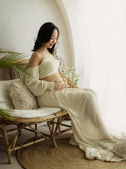 A moment of peace. Seated on a rattan bench, this mom-to-be enjoys a quiet moment, beautifully lit by the window.