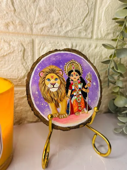 Another look at the hand-painted Durga coaster, showing how it looks from a different angle with some greenery. It comes with a golden stand for easy display.