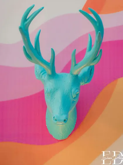 A turquoise deer head mounted on a vibrant, wavy backdrop, continuing the theme of colorful, artistic animal motifs.