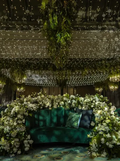 An emerald green velvet sofa, enveloped in a cloud of white flowers and set under a ceiling of fairy lights. This sangeet seating was designed to be a showstopper, a perfect photo-op spot that felt both glamorous and ethereal.