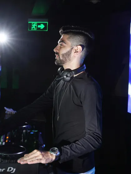 A profile shot of me at the Pioneer DJ console, with headphones around my neck, ready for the next transition. This highlights the professional-grade equipment I use for all my gigs.