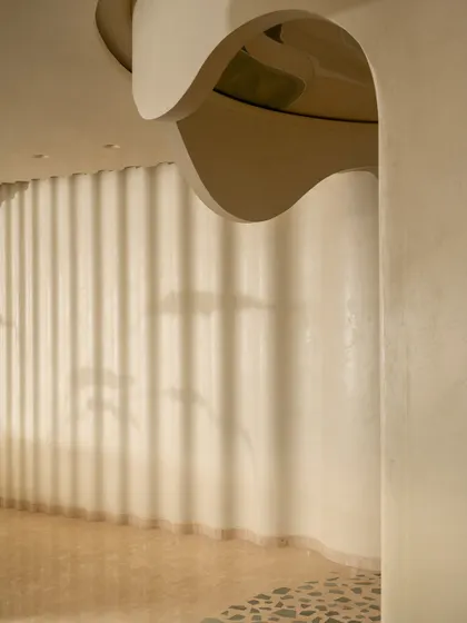A detail of the coffee corner, where the wall has a rippled texture and shadows from a nearby window create a beautiful, transient pattern.