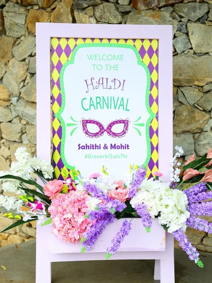 A welcome sign for a "Haldi Carnival," featuring a fun masquerade theme and a vibrant color palette.