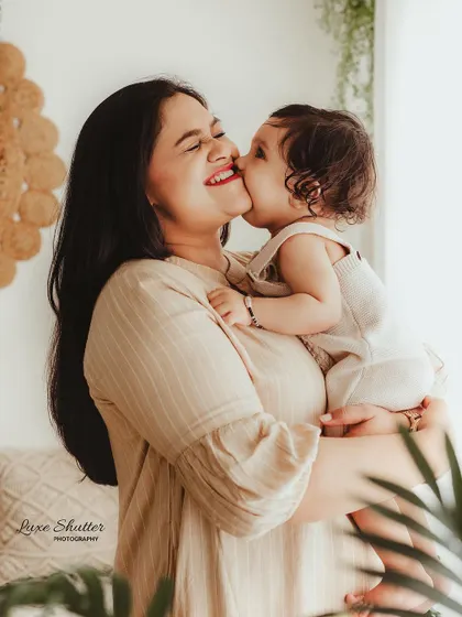 A playful and joyful moment between a mother and her baby. The baby's sweet kiss on the cheek and the mother's resulting laughter are priceless.